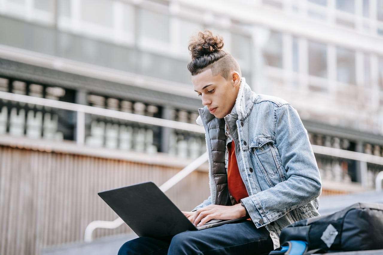 Young person sitting outside typing on computer